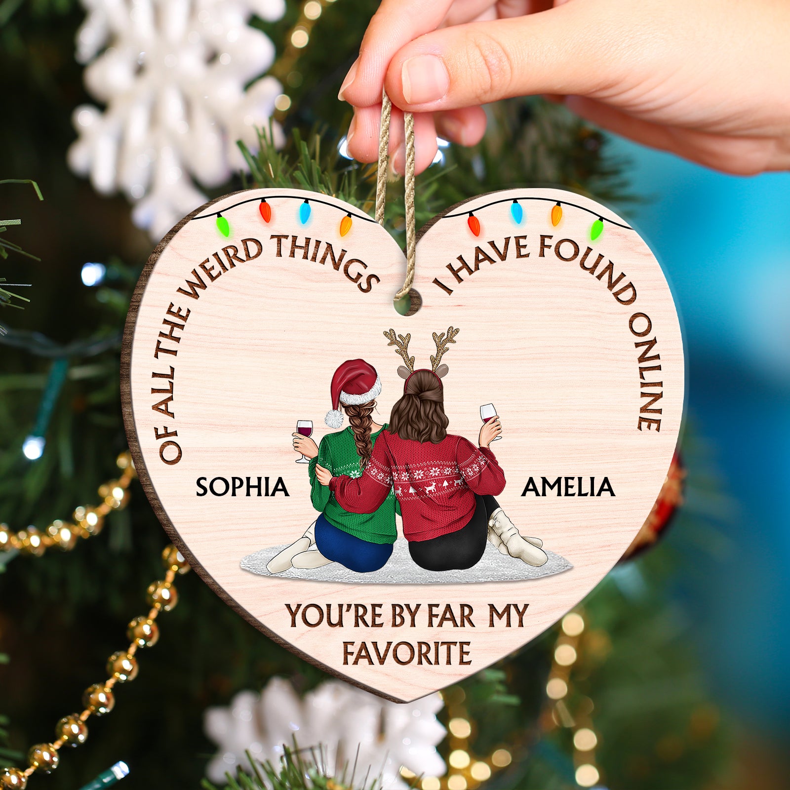 Close-up of a wooden heart ornament showing a couple relaxing with drinks and festive holiday light graphics