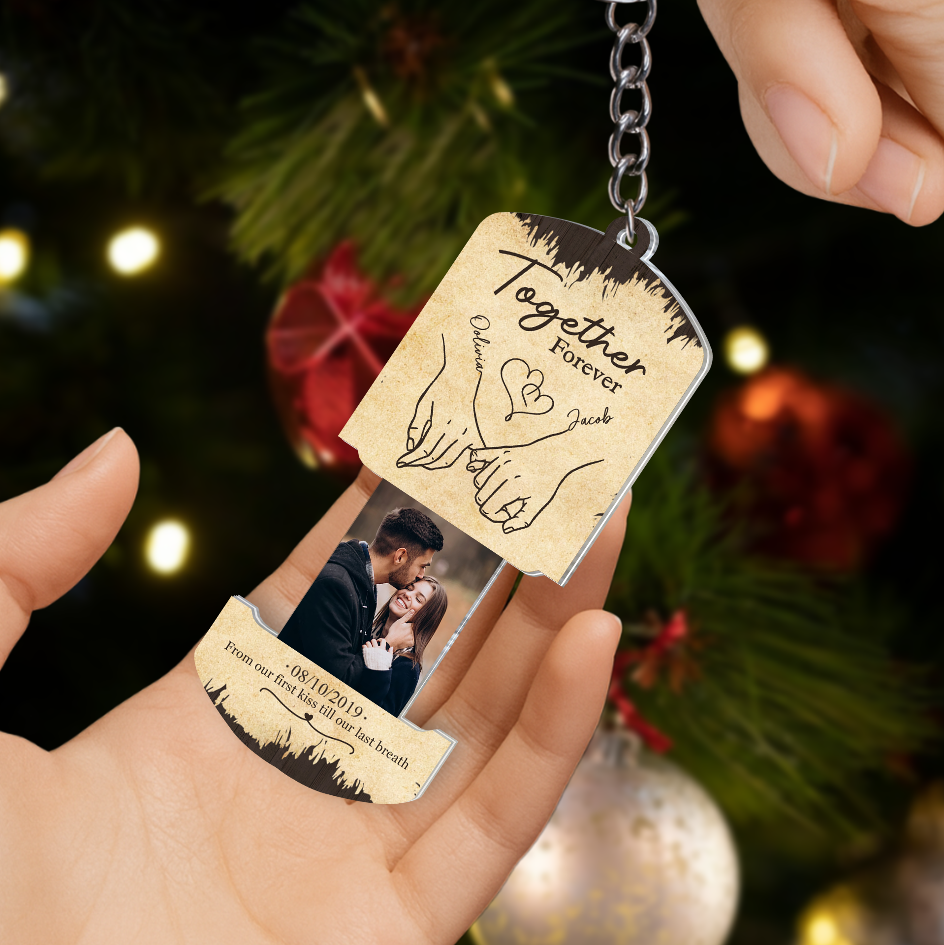 Custom photo sliding keychain held by a hand in front of a warm Christmas tree background with festive holiday lighting